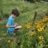 child adding cut flowers to a recycled card